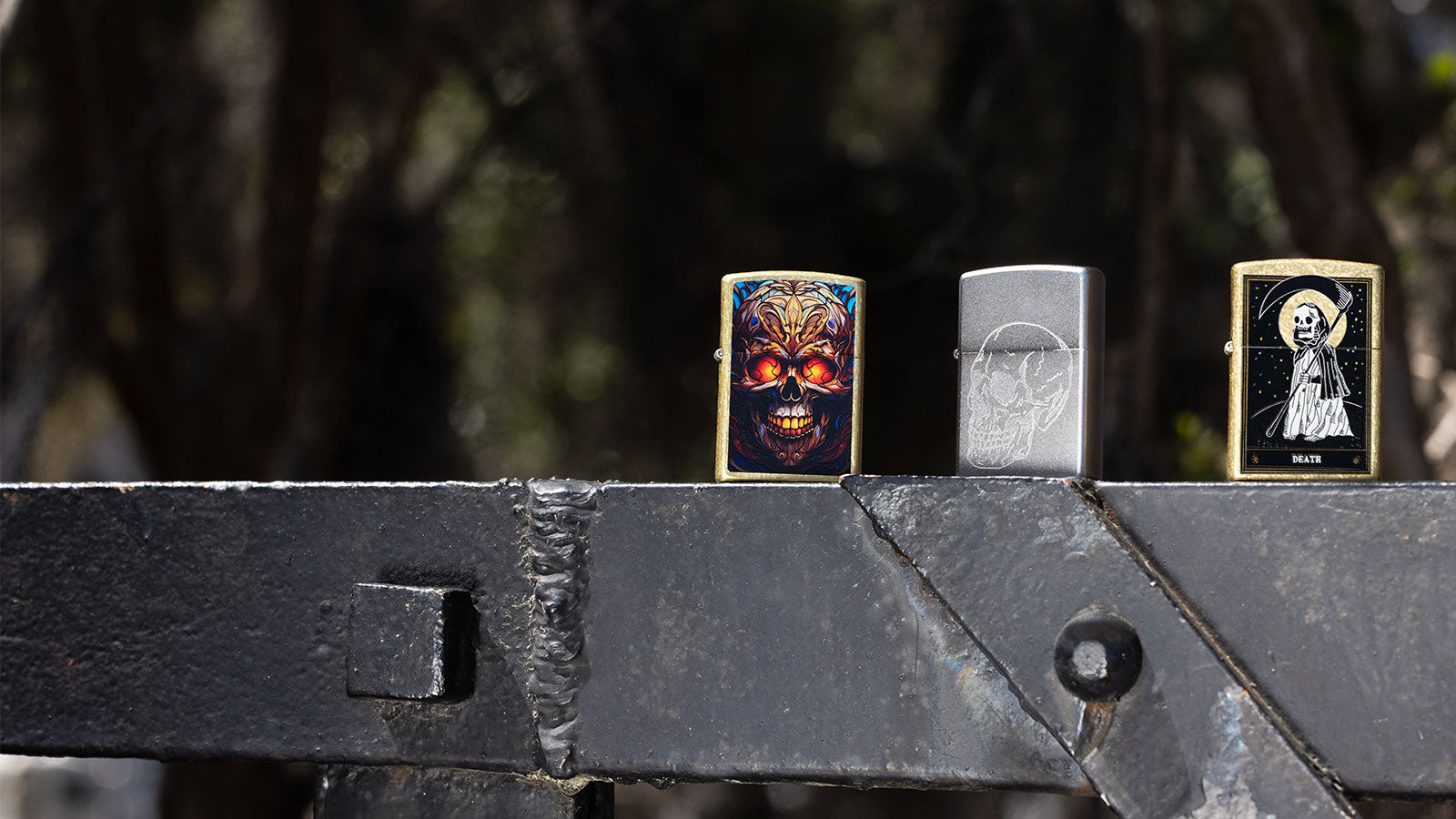 Three skull themed lighters on a steel rail.