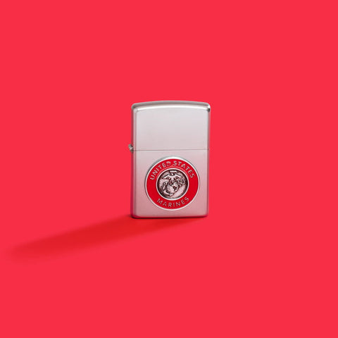 Lifestyle image of Zippo United States Marines Emblem Satin Chrome Windproof Lighter on a red background.