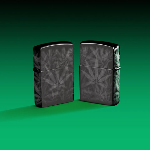 Lifestyle image of two Zippo Cannabis Design High Polish Black Windproof Lighters on a green ombre background.