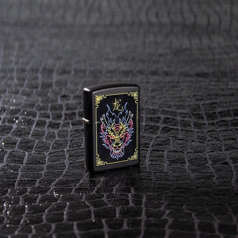 Lifestyle image of Neon Dragon Design Black Matte Windproof Lighter standing on a black scale textured surface