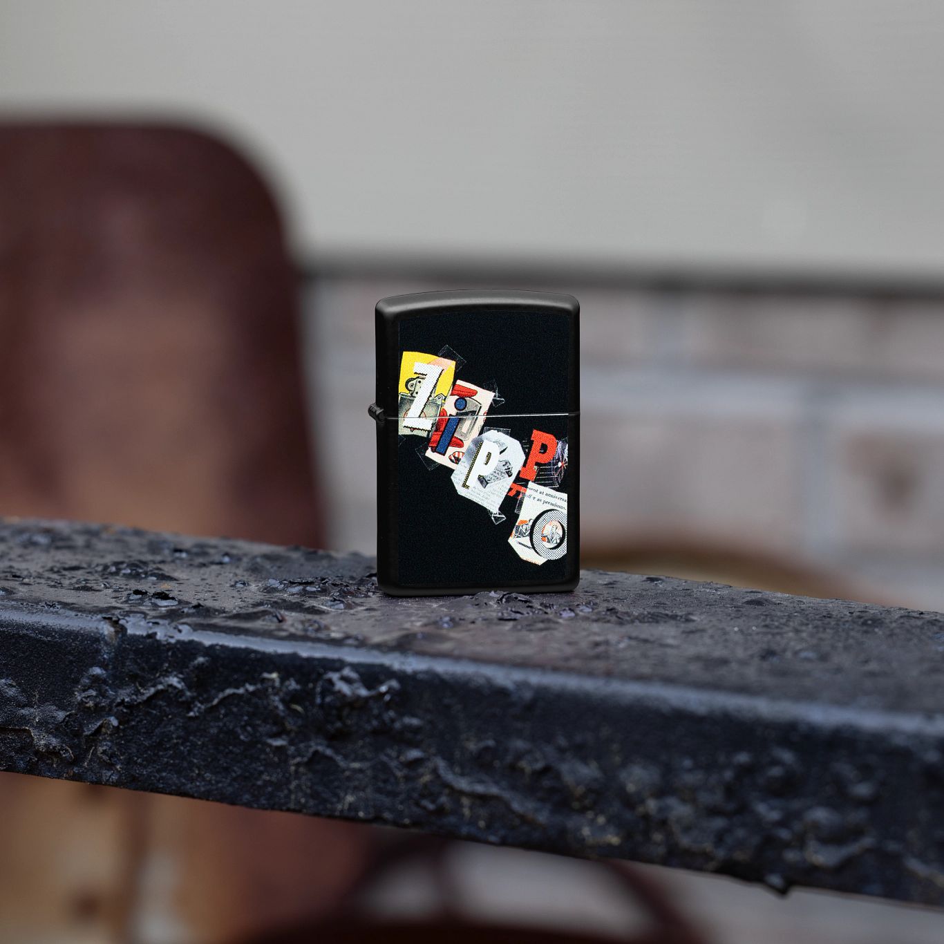 Lifestyle image of Zippo Cut and Paste Design Black Matte Windproof Lighter standing on a wrought iron fence.