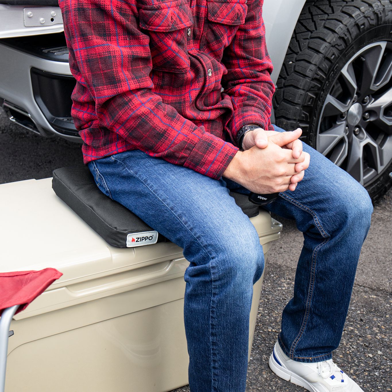Lifestyle image of Zippo Heated Seat - Single, with a man sitting on it at a tailgate.