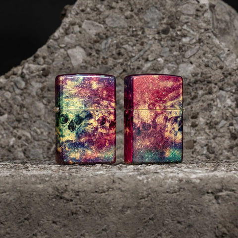 Lifestyle image of two Zippo Galaxy Skull Design 540 Tumbled Brass Windproof Lighters standing in front of a rock background.