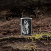 Lifestyle image of Zippo Lindsay Kivi Shadow Wolf Street Chrome Windproof Lighter standing on a mossy outdoor background.
