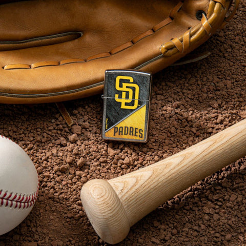 Lifestyle image of MLB® San Diego Padres™ Street Chrome™ Windproof Lighter laying on a baseball field with a glove, ball, and bat.