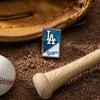 Lifestyle image of MLB® Los Angeles Dodgers™ Street Chrome™ Windproof Lighter laying on a baseball field with a glove, ball, and bat.