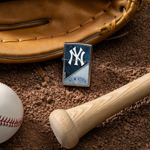 Lifestyle image of MLB™ New York Yankees™ Street Chrome™ Windproof Lighter laying on a baseball field with a glove, ball, and bat.