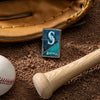 Lifestyle image of MLB® Seattle Mariners™ Street Chrome™ Windproof Lighter laying on a baseball field with a glove, ball, and bat.
