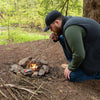 Lifestyle image of man using the collapsible manual bellows to add oxygen to the fire to get it roaring