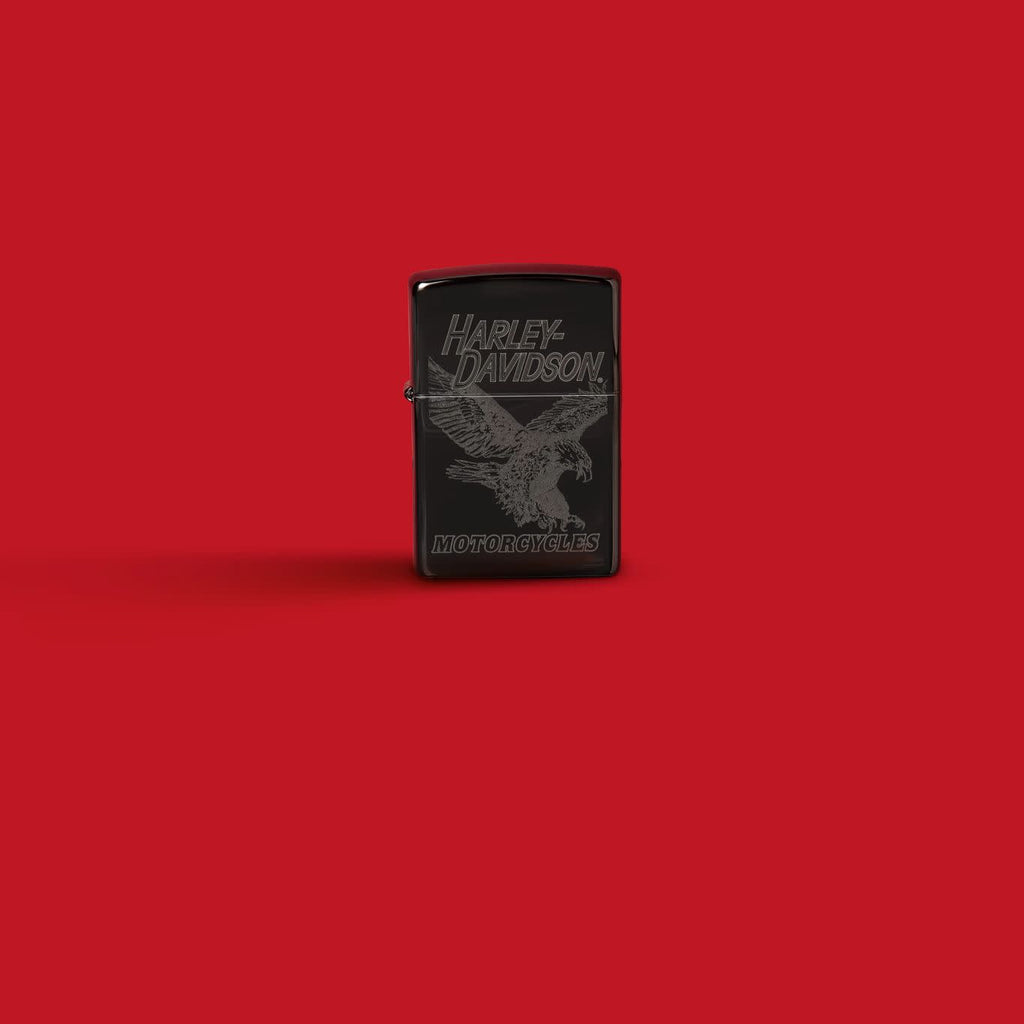 Glamour shot of Zippo Harley-Davidson Laser Fancy Fill High Polish Black Windproof Lighter standing in a red scene.