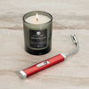 Lifestyle image of Candy Apple Red Rechargeable Candle Lighter & 8 oz Driftwood & Sea Salt Candle lit on a countertop.