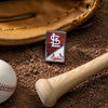 Lifestyle image of MLB® St. Louis Cardinals™ Street Chrome™ Windproof Lighter laying on a baseball field with a glove, ball, and bat.