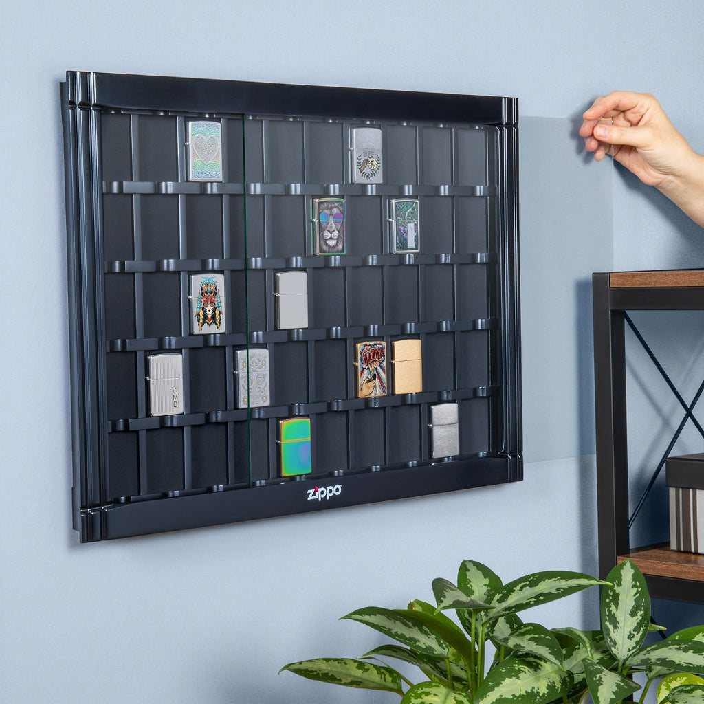 Lifestyle image of 50 piece black lighter display handing on the wall. The display has lighters in it and a person sliding in the display;s glass panel.