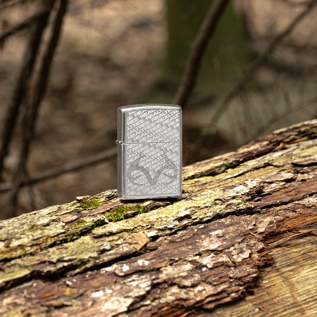 Lifestyle image of Zippo RealTree High Polish Chrome Windproof Lighter standing outside on a log.