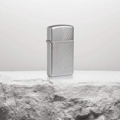 Lifestyle image of SlimÂ® Zippo Dot Design Satin Chrome Windproof Lighter standing on a white rock pedestal. 