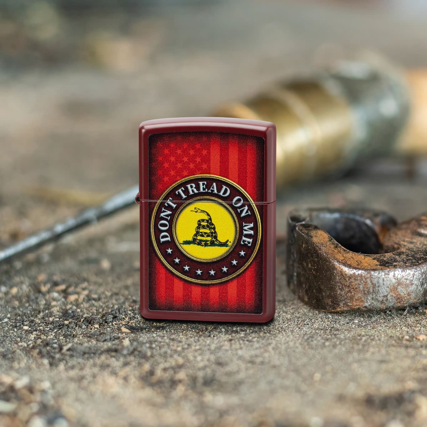 Lifestyle image of Zippo Dont Tread on MeÂ® Merlot Windproof Lighter standing on a dirty surface with pliers and a screwdriver behind.