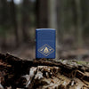 Lifestyle image of Zippo Campfire Design Navy Matte Windproof Lighter standing on a moss covered log.