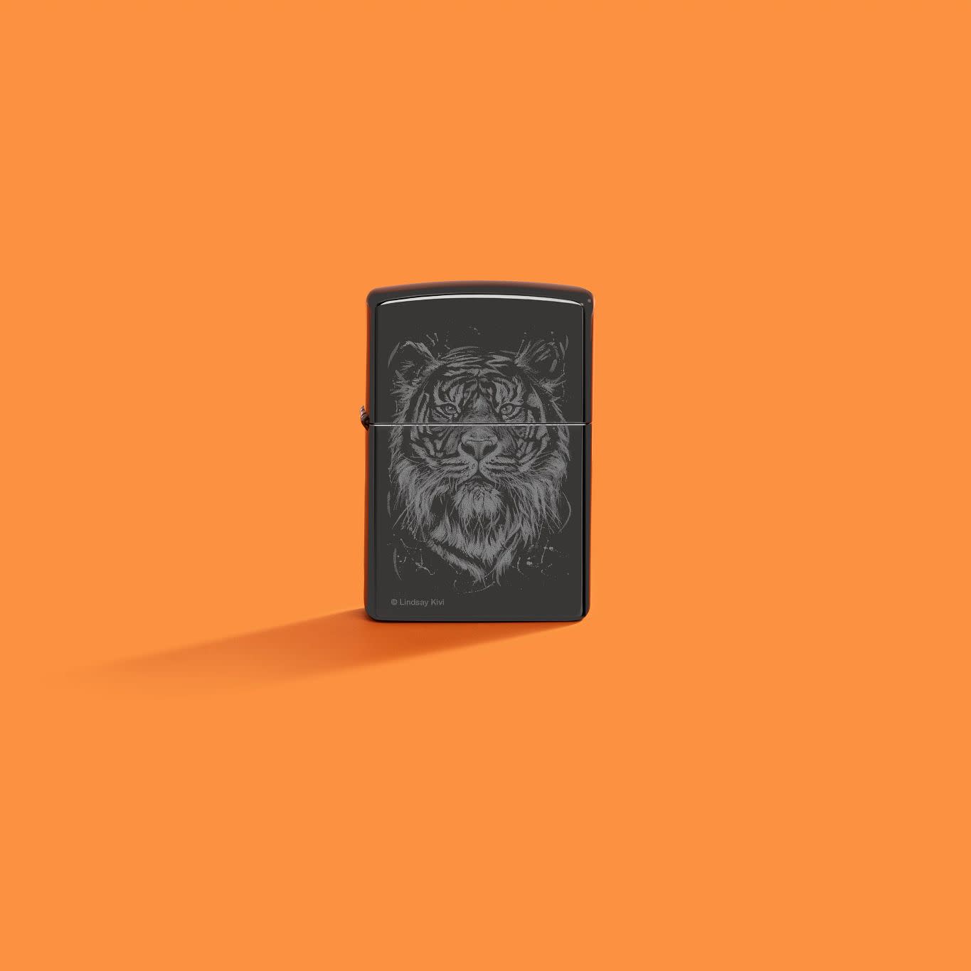 Lifestyle image of Zippo Lindsay Kivi High Polish Black Windproof Lighter on an orange background.