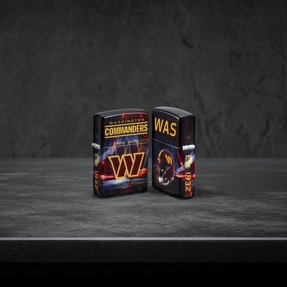 Lifestyle image of two Zippo NFL Washington Commanders 540 Matte Windproof Lighters, one showing the front of the lighter and the other showing the back, standing on a dark grey surface.