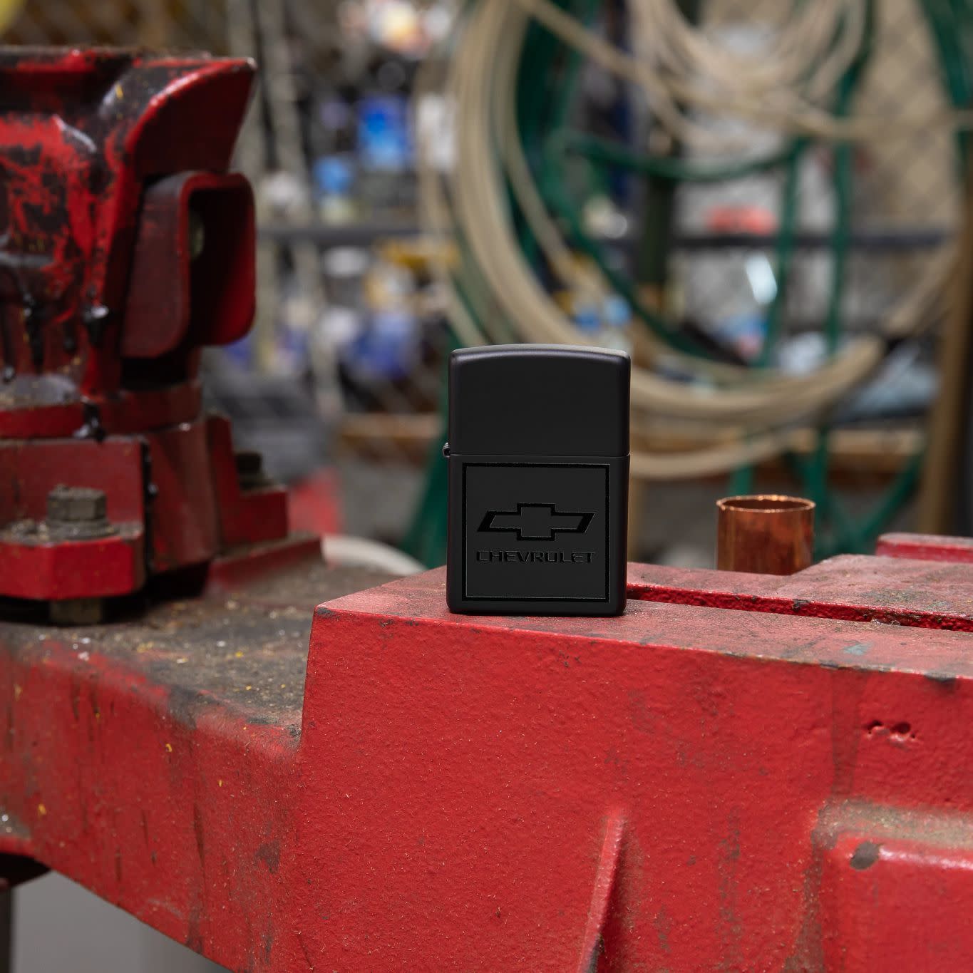 Lifestyle image of Zippo ChevroletÂ® Bowtie Design Black Matte Windproof Lighter in an auto shop setting.