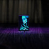 Lifestyle image of Zippo Glowing Skull Design Black Matte Windproof Lighter glowing in a black light.