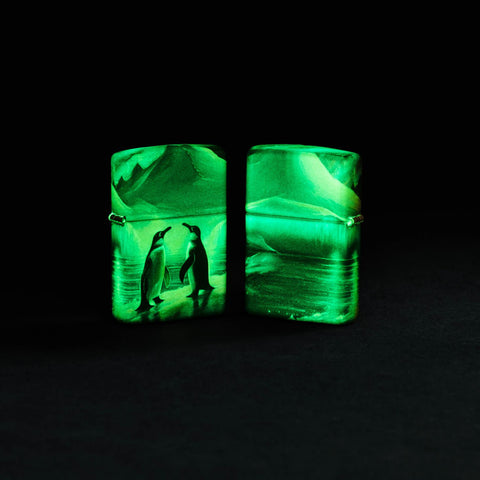 Lifestyle image of two Zippo Penguin Design Glow in the Dark Green Matte Windproof Lighters glowing in the dark.