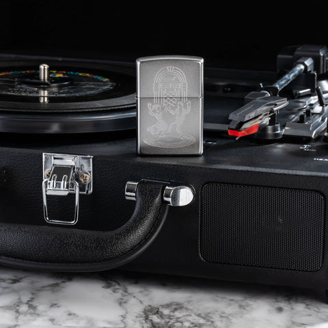 Lifestyle image of Zippo Vintage Dance Design Satin Chrome Windproof Lighter sitting on a record player.