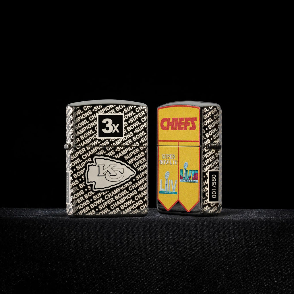 Lifestyle image of two Zippo NFL Kansas City Chiefs Super Bowl Commemorative Armor Black Ice Windproof Lighters with a black background.