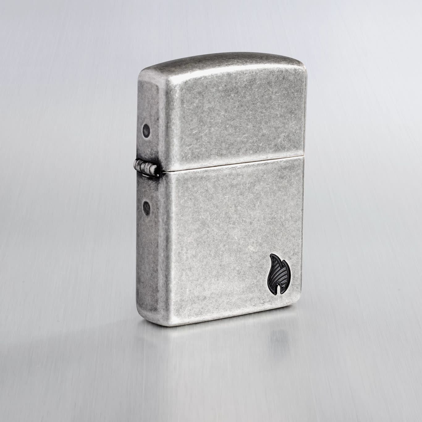 Lifestyle image of Zippo ArmorÂ® Series Flame Antique Silver Windproof Lighter on a light gray background.