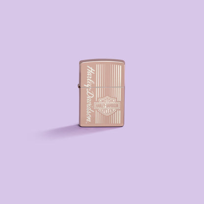 Lifestyle image of Zippo Harley-DavidsonÂ® High Polish Rose Gold Windproof Lighter on a pastel purple background.