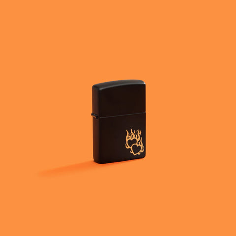 Lifestyle image of Zippo Fire Heart Design Black Matte Windproof Lighter on an orange background.