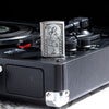 Lifestyle image of Zippo Roller Waitress Emblem Brushed Chrome Windproof Lighter sitting on a record player.
