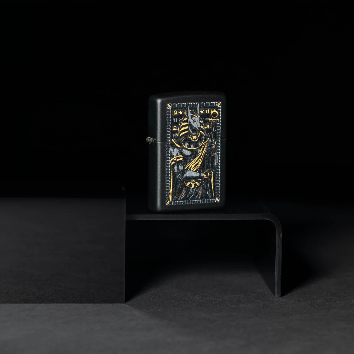 Lifestyle image of Zippo Anubis Design Black Matte Windproof Lighter standing on a platform in the dark.