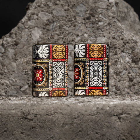 Lifestyle image of two Zippo Tapestry Pattern Design 540 Tumbled Chrome Windproof Lighters standing on a stone background.