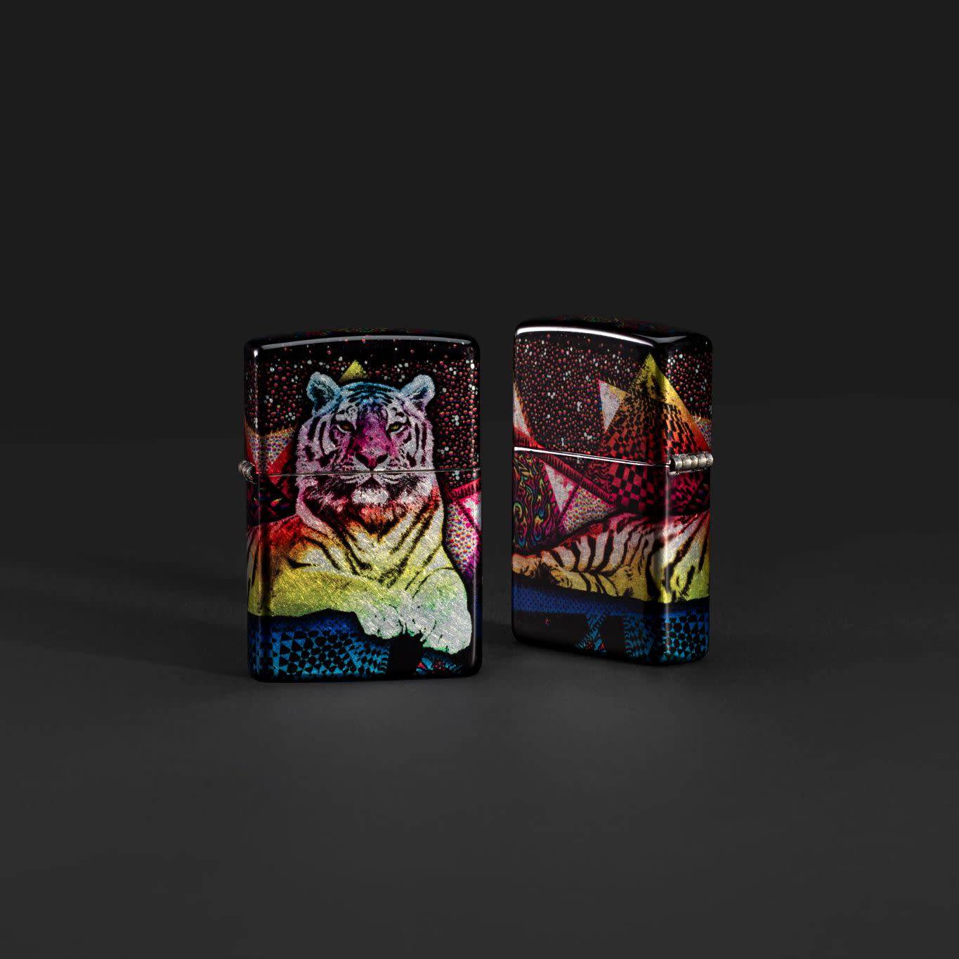 Lifestyle image of two Zippo Tiger Glory 540 Tumbled Chrome Windproof Lighters on a black background.