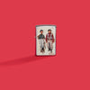 Lifestyle image of Zippo Norman Rockwell Fishing Street Chrome Windproof Lighter on a red background.