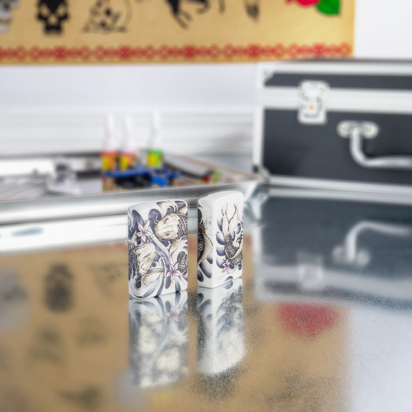 Lifestyle image of two Koi Fish 540 Color Windproof Lighters standing on a table with tattoo equipment.