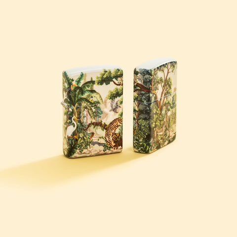 Lifestyle image of two Zippo Jungle Design 540 Matte Windproof Lighters on a pale yellow background.
