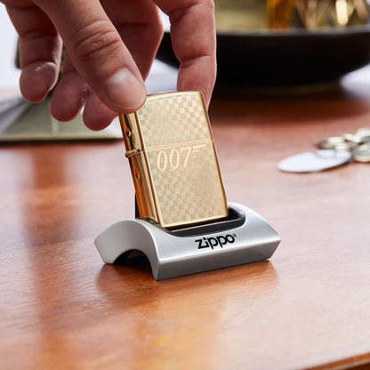 Lifestyle image of Zippo Textured James Bond 007â„¢ Design Brushed Brass Windproof Lighter sitting in a display stand on a desk.