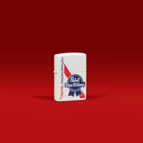Lifestyle image of Zippo Pabst Blue Ribbon Design White Matte Windproof Lighter standing in a red scene.