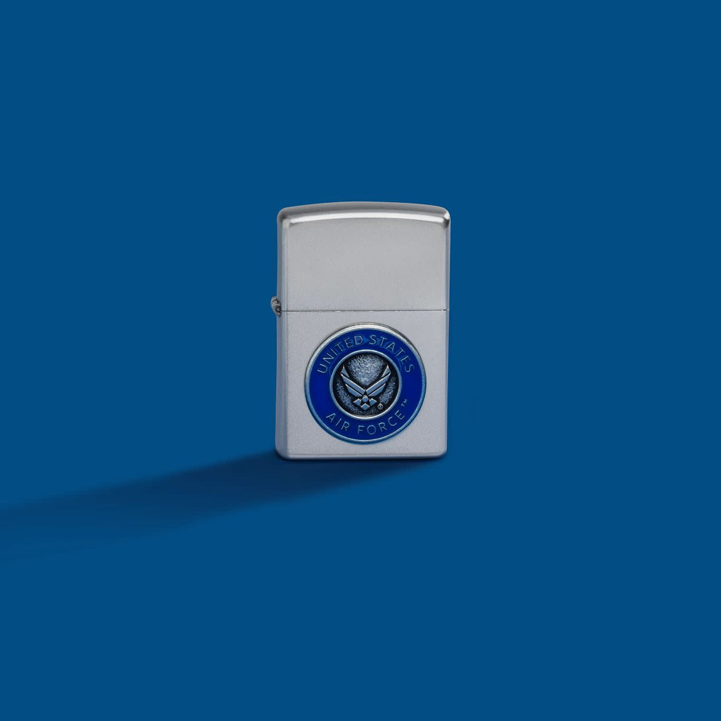 Lifestyle image of Zippo United States Air Force™ Emblem Satin Chrome Windproof Lighter on a blue background.