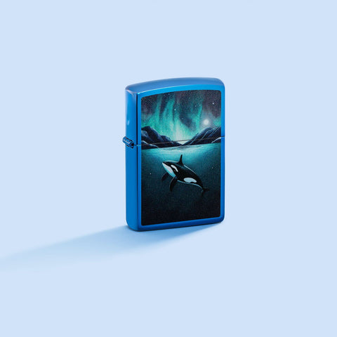 Lifestyle image of Zippo Whale Design High Polish Blue Windproof Lighter on a pale blue background.