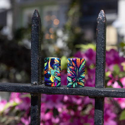 Lifestyle image of two Zippo Cannabis Camo Design 540 Matte Windproof Lighters, one showing the front and right side of the lighter and the other showing the back and rightt side of the lighter, both standing on an iron fence.