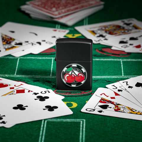 Lifestyle image of Zippo Poker Chip with Cherries Emblem Black Matte Windproof Lighter sitting on a card table.