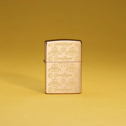 Lifestyle image of Zippo Crown Royal Elegance Design Brushed Brass Windproof Lighter standing with a mustard yellow background.
