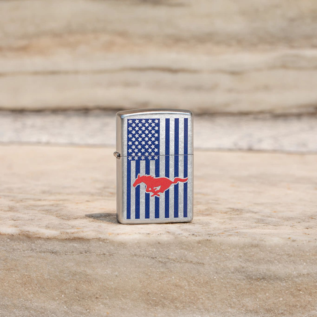 Lifestyle image of Zippo Ford Mustang American Flag Street Chrome Windproof Lighter standing on stone.