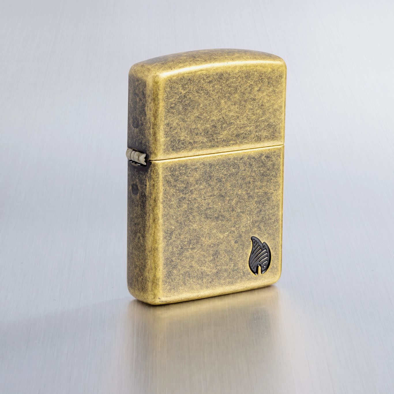 Lifestyle image of Zippo ArmorÂ® Series Flame Antique Brass Windproof Lighter on a light gray background.