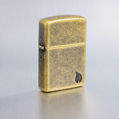 Lifestyle image of Zippo ArmorÂ® Series Flame Antique Brass Windproof Lighter on a light gray background.