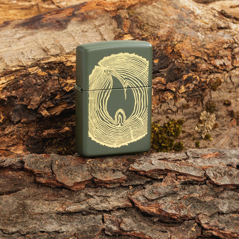 Lifestyle image of Zippo Wood Ring Design Green Matte Windproof Lighter sitting in a log.
