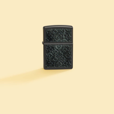Lifestyle image of Zippo Pattern Design High Polish Black Windproof Lighter on a pale yellow background.